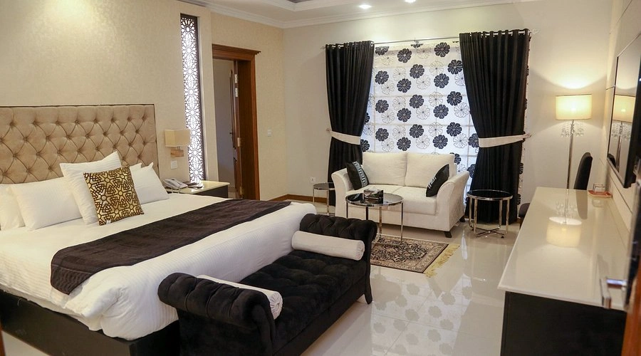 Luxury guest house room in Islamabad with a king bed, modern décor, seating area, and elegant lighting for a relaxing stay in 2026.